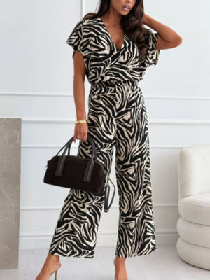 Zebra print wide-leg romper with V-neck and short sleeves, styled with a handbag.