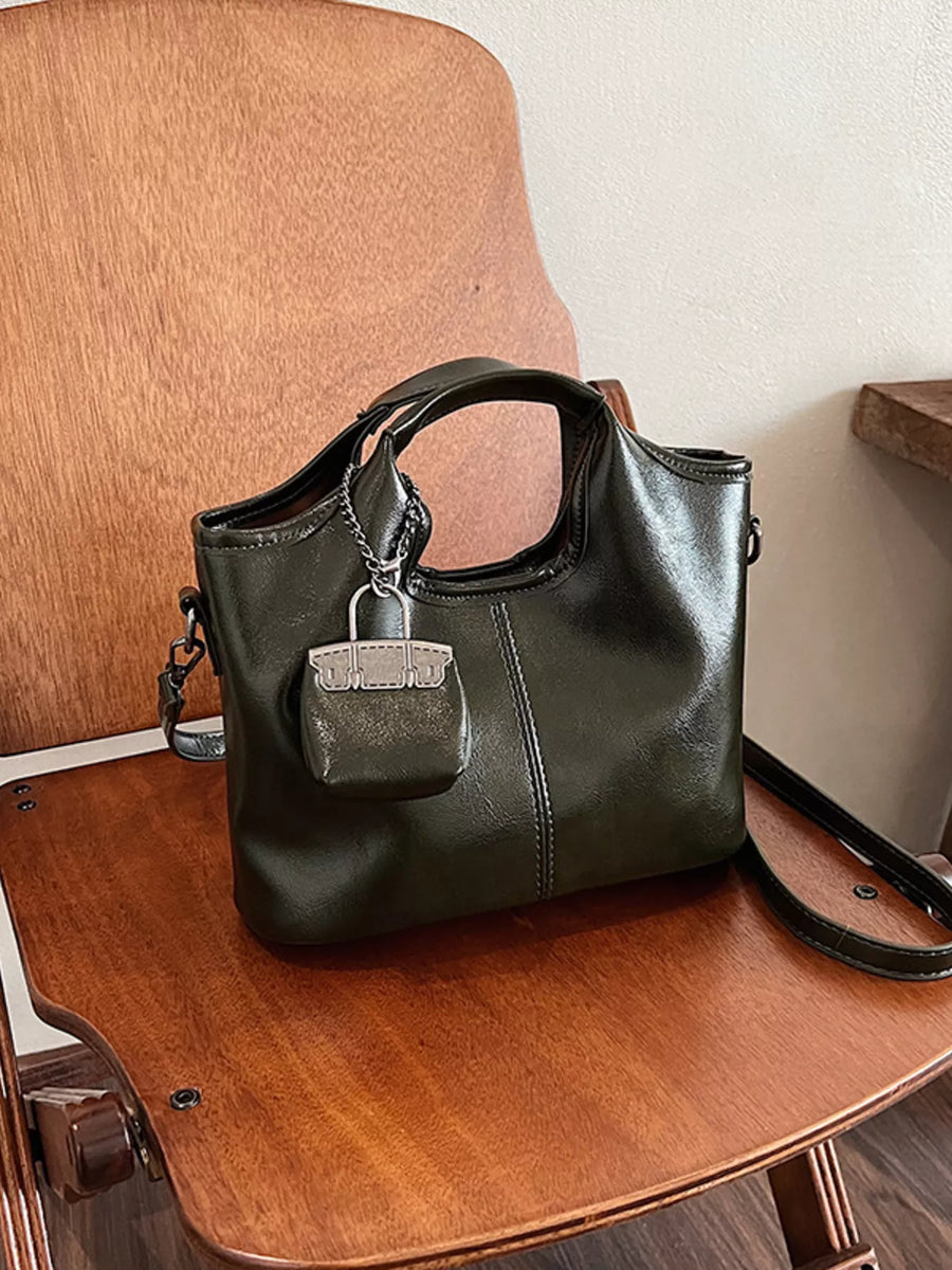 Chic PU leather crossbody bag in dark green with a mini bag charm and silver hardware.