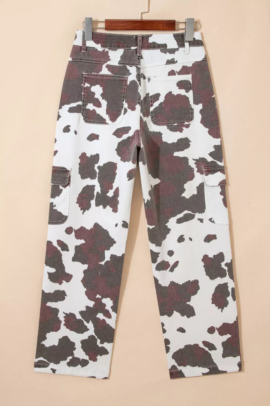 Cow print utility jeans with cargo pockets and a cotton blend fabric.