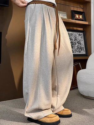 Loose fit sweatpants in khaki with drawstring and pockets, styled with casual shoes.