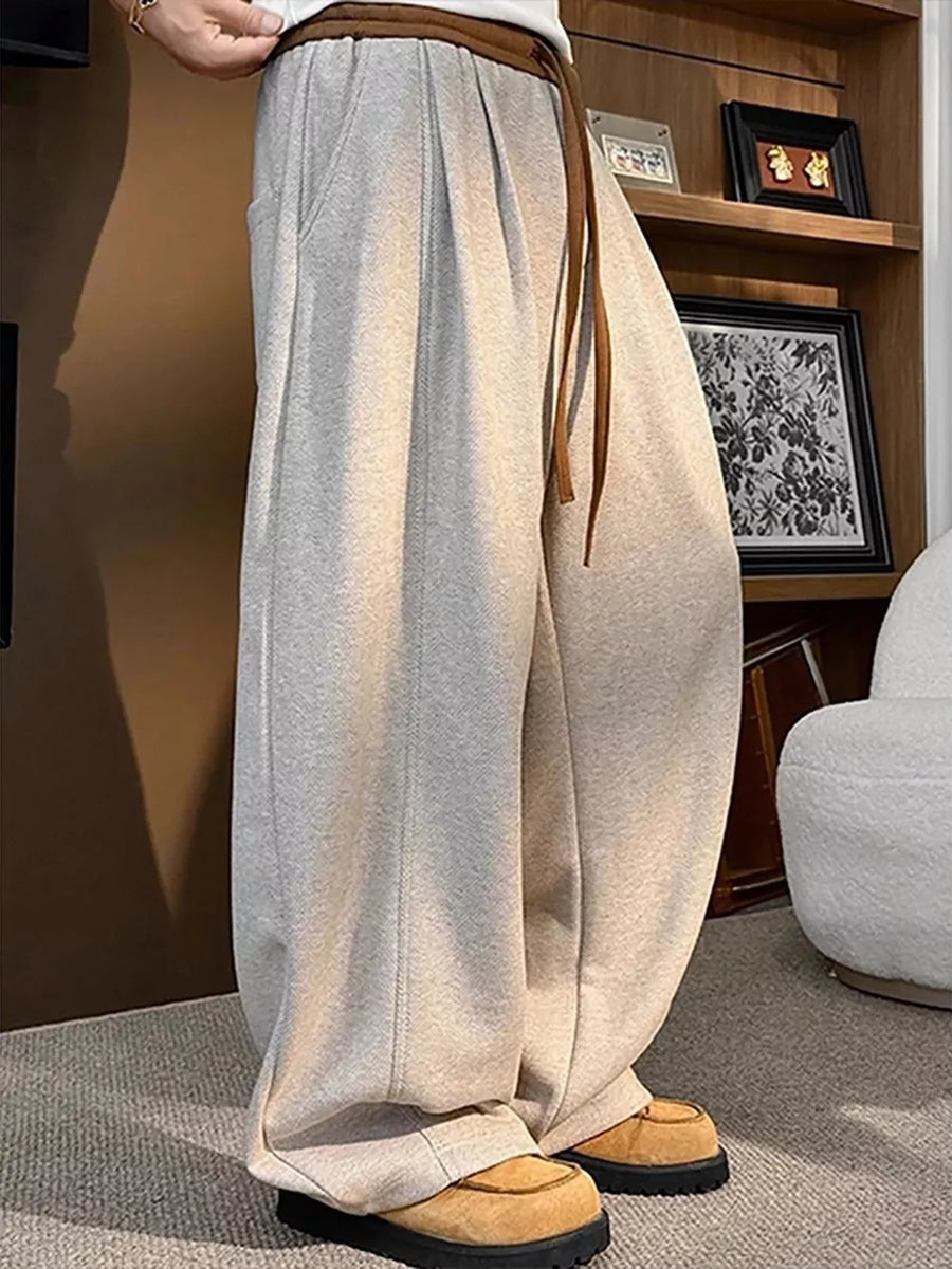 Loose fit sweatpants in khaki with drawstring and pockets, styled with casual shoes.