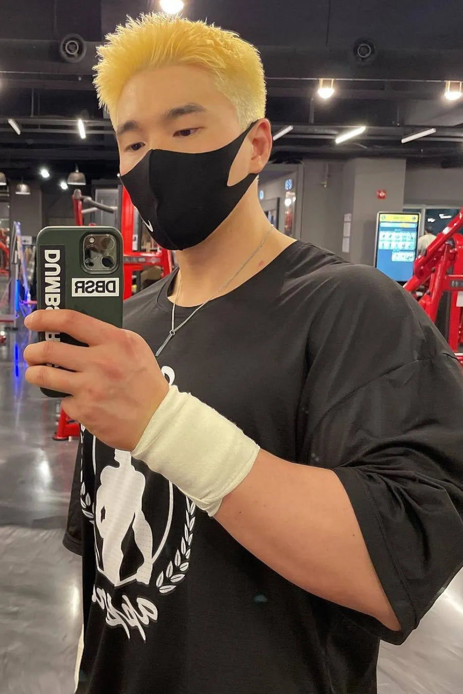 Black oversized graphic t-shirt with crew neck and short sleeves, worn by a man in a gym.