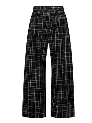 Plaid wide-leg men's sweatpants in black with white check pattern and drawstring waist.