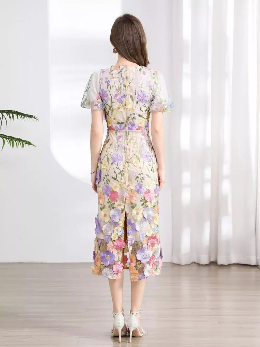 Sheath dress with colorful floral embroidery, short sleeves, and a midi length with a back slit.