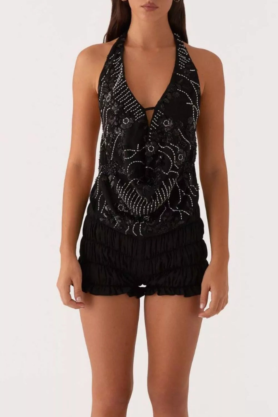 Black halter top with white embroidery and sequin detail, paired with ruched black shorts.