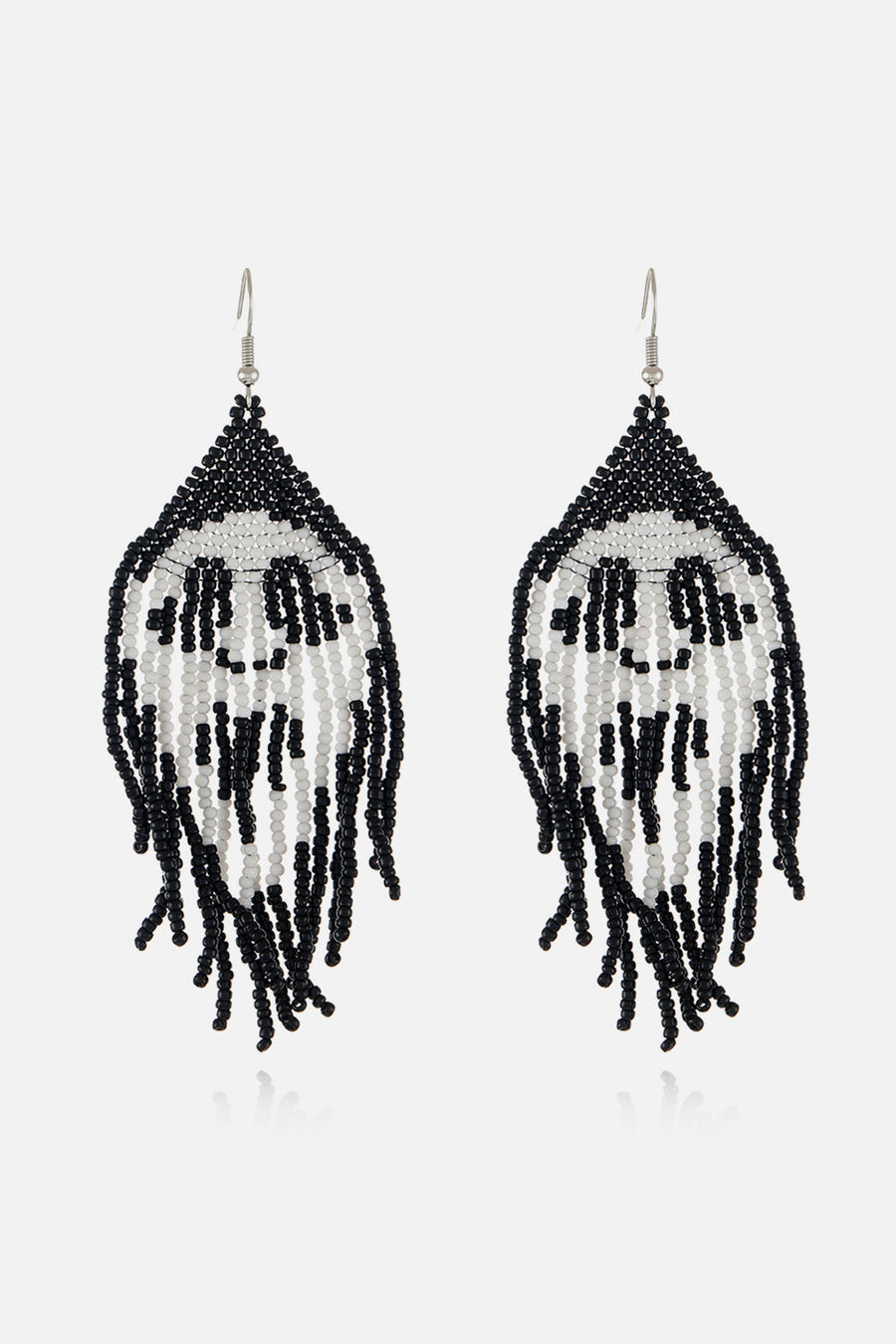 Beaded skull fringe earrings in black and white with dangling strands.