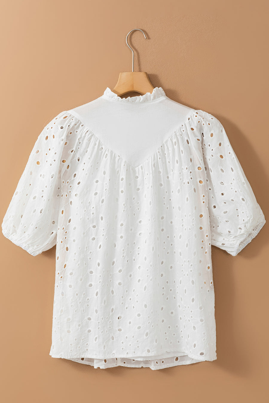 White eyelet puff-sleeve blouse with stand collar and ruffled neckline.
