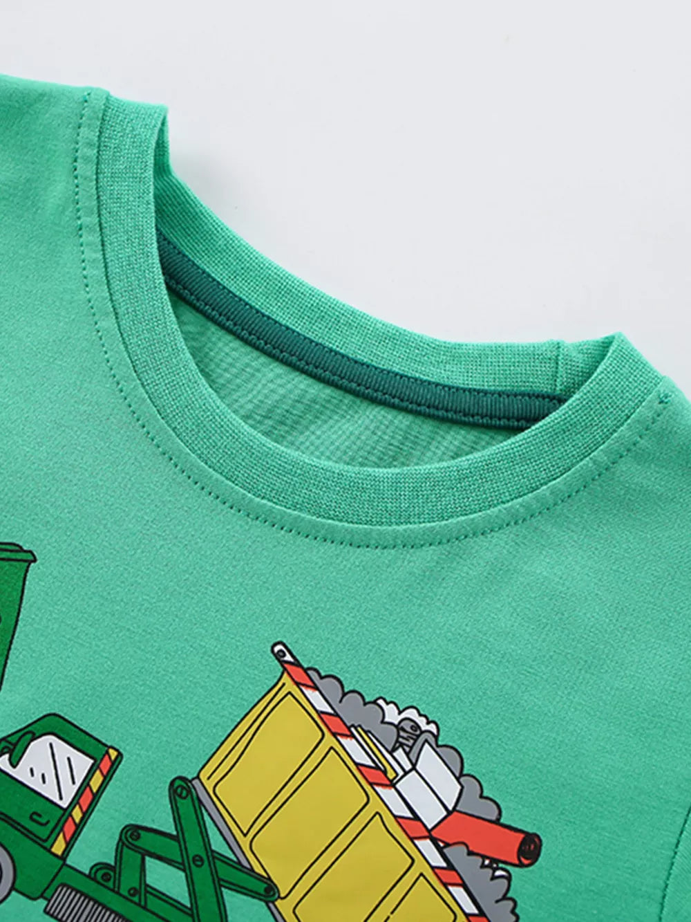 Green cotton t-shirt with a whimsical truck print and a dark green ribbed neckline.