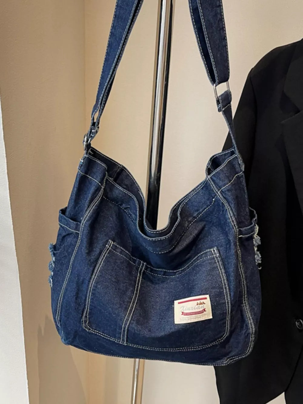 Slouchy denim crossbody bag in blue with contrast stitching and adjustable strap.