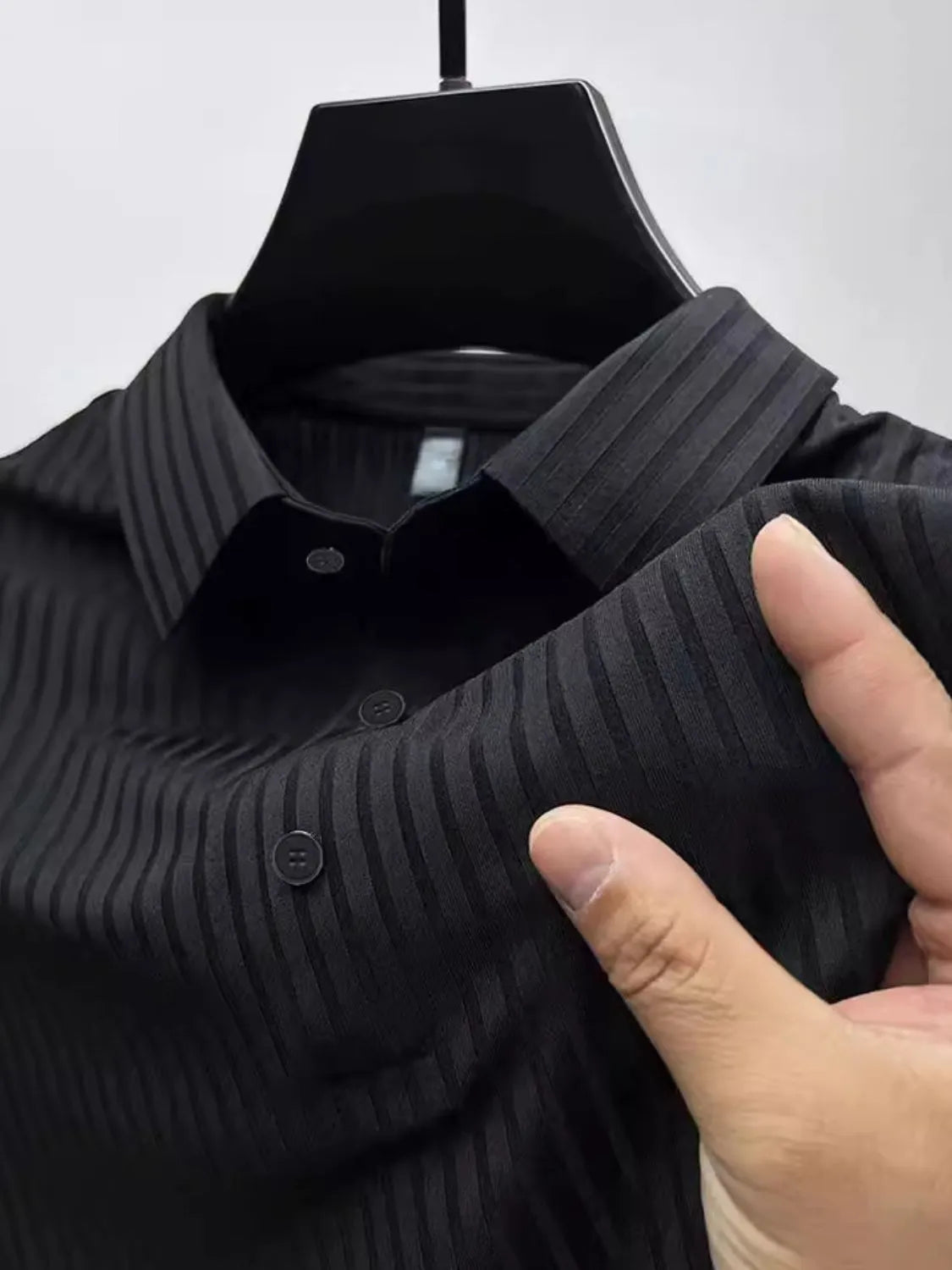 Black ribbed polo shirt with buttoned collar and textured vertical stripes.