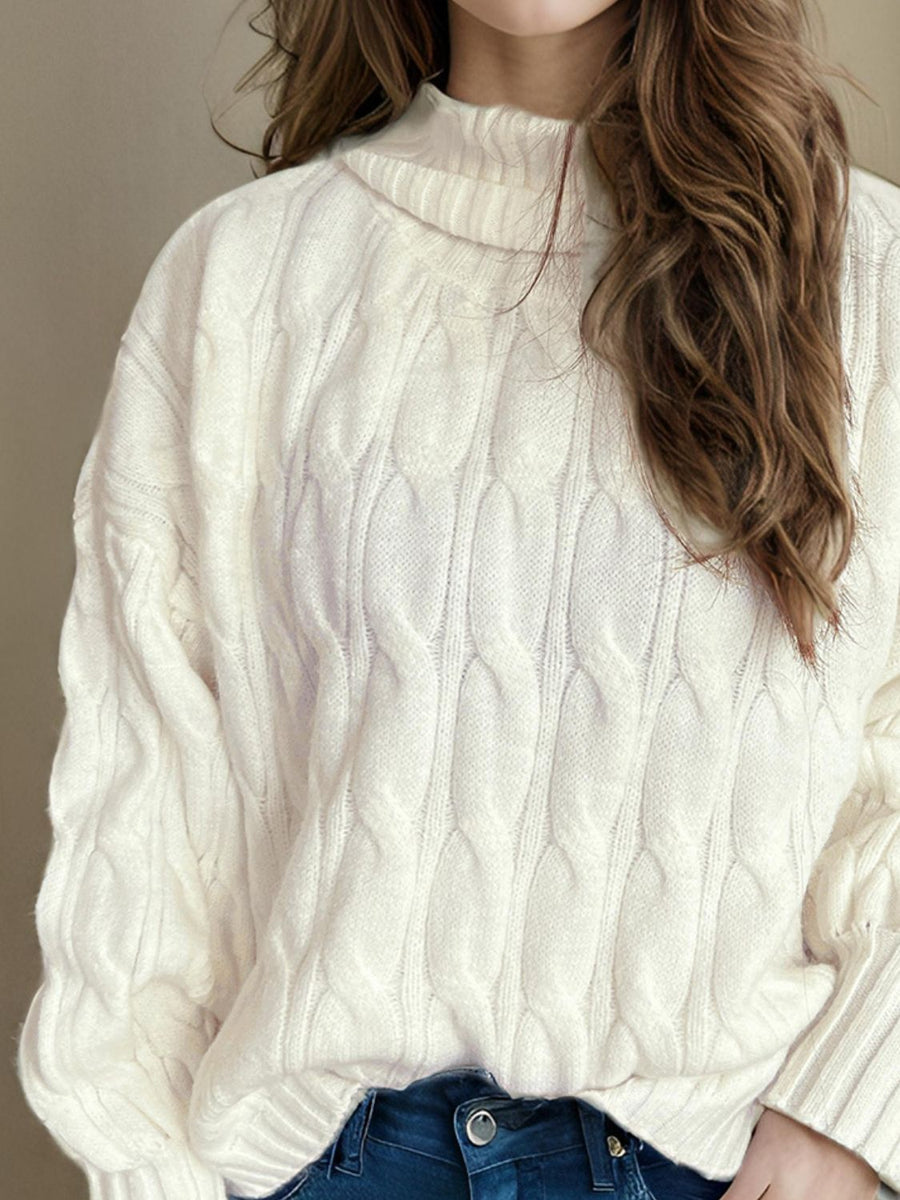 Ivory oversized cable knit turtleneck sweater with prominent cable detailing.