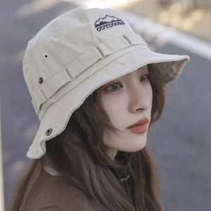 Bucket hat in beige cotton with embroidered mountain logo and adjustable straps.