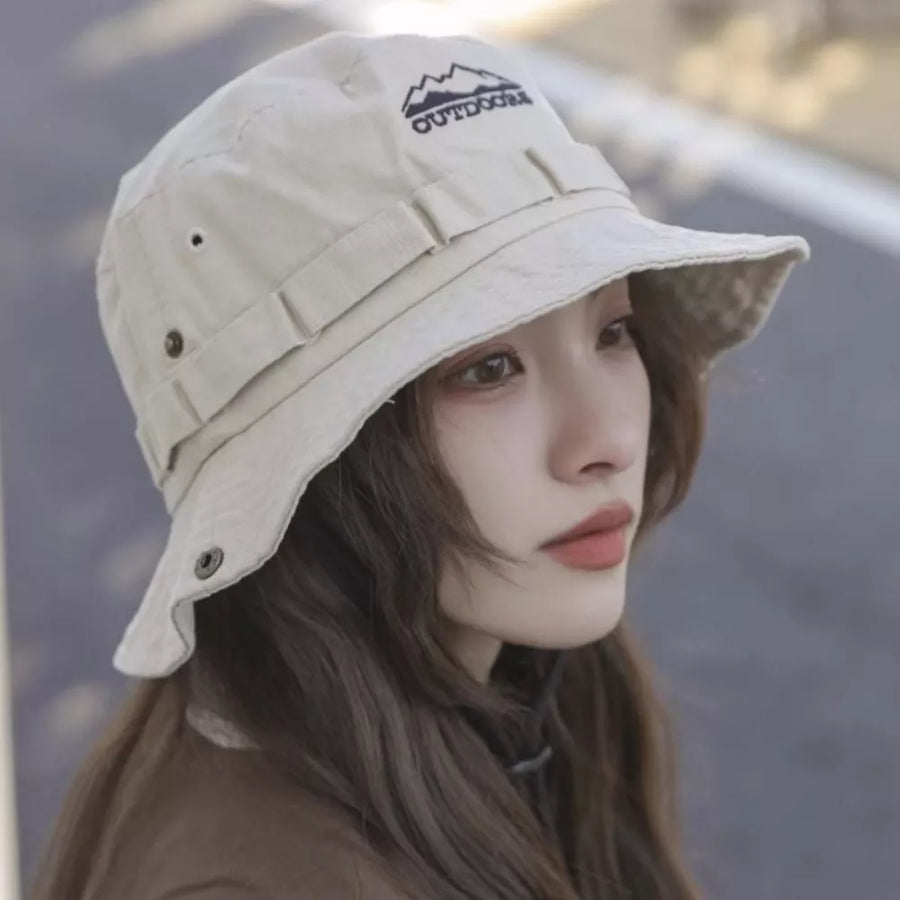Bucket hat in beige cotton with embroidered mountain logo and adjustable straps.