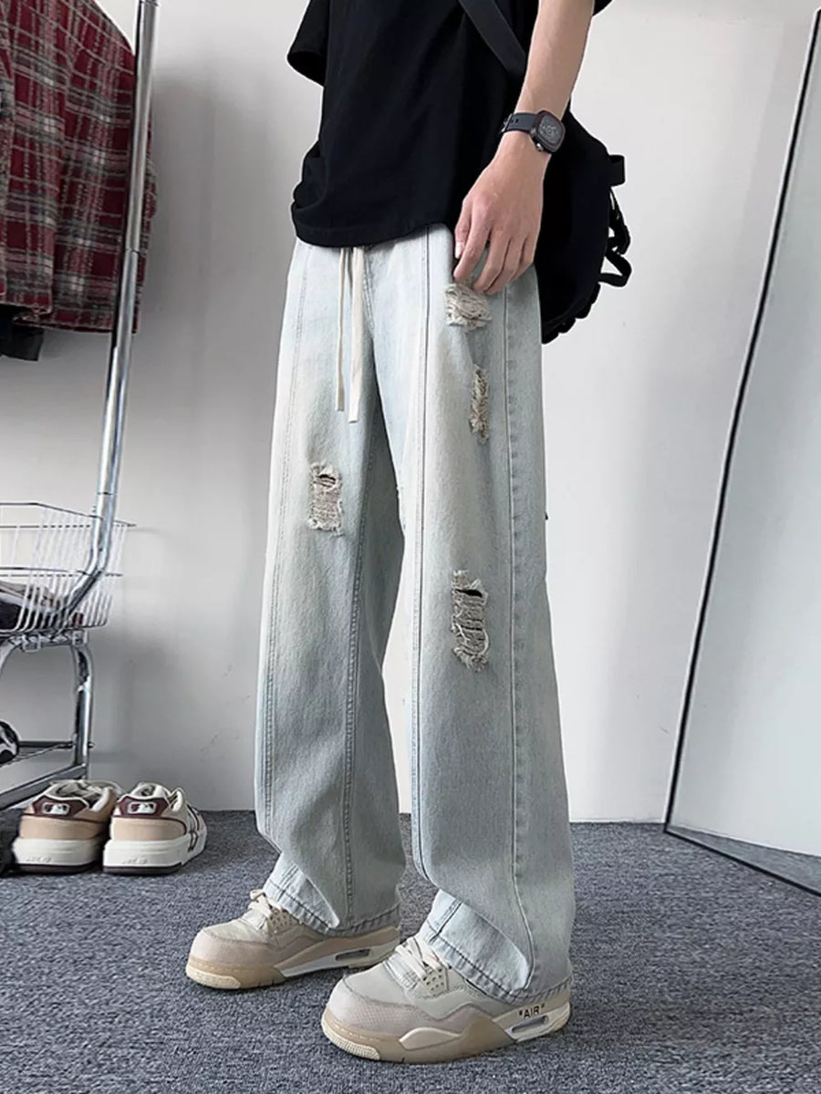 Oversized light blue distressed wide-leg jeans with drawstring waist.