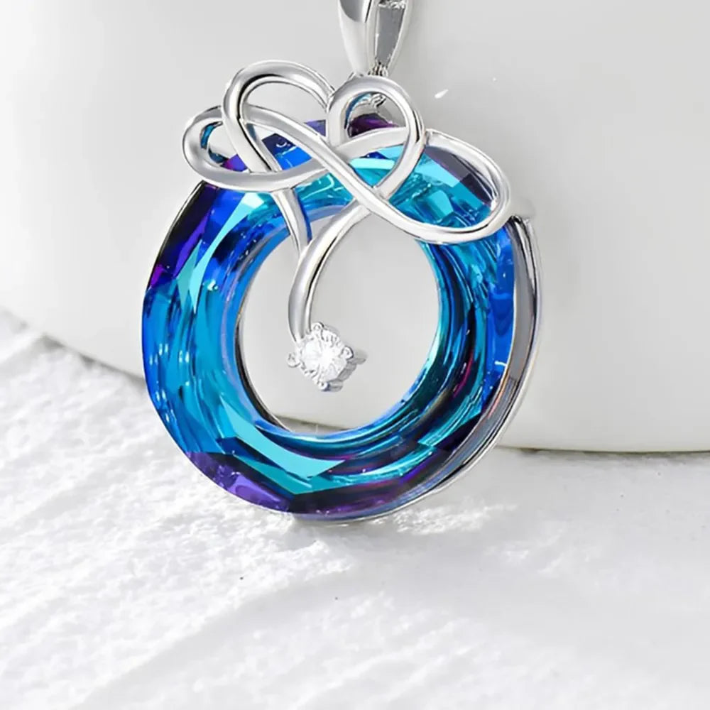 Infinity knot crystal pendant necklace in royal blue with a small diamond accent.