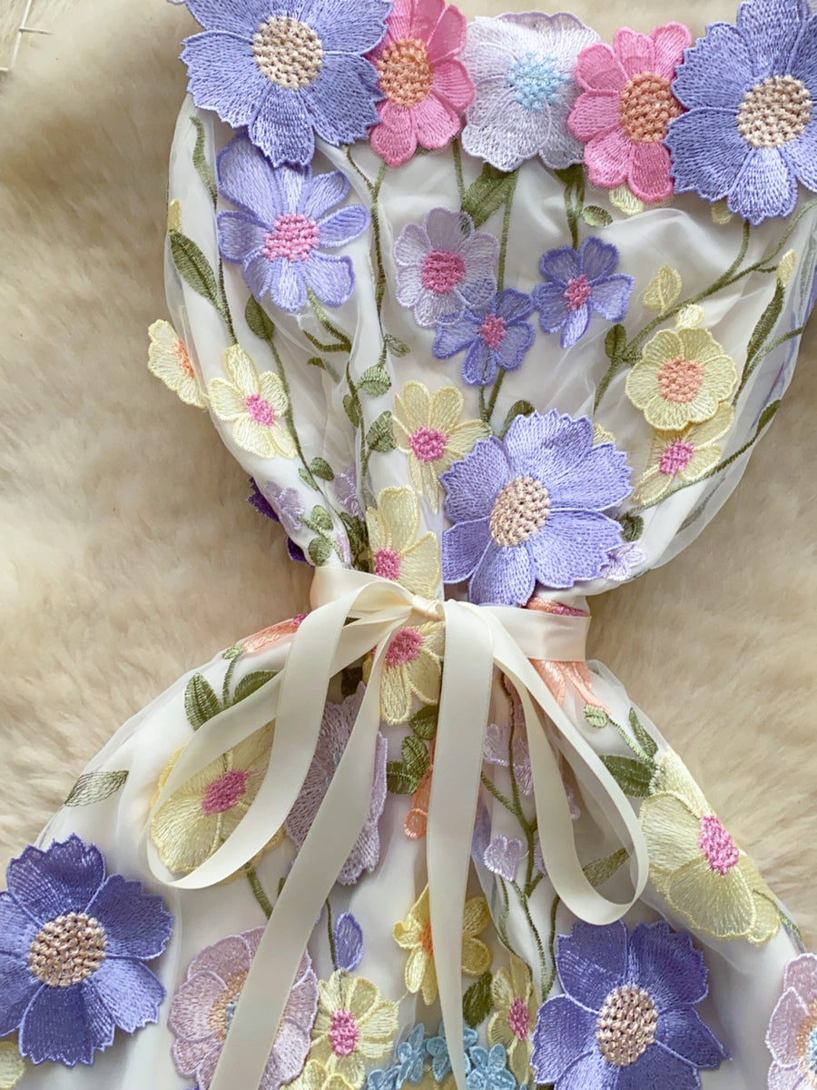 Embroidered floral mini dress in white with colorful flower appliques and a ribbon bow detail.