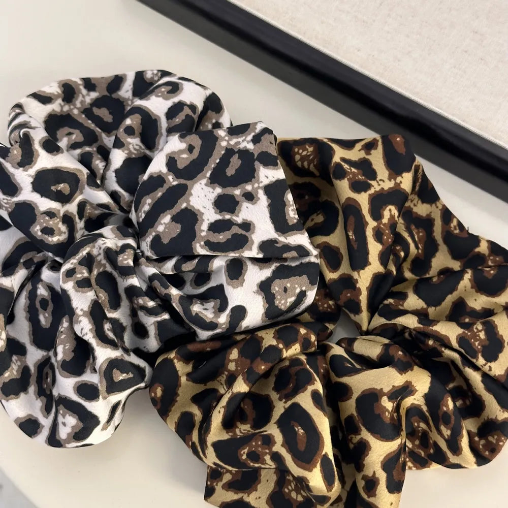 Leopard print silk scrunchies in tan and white, chic hair accessories for women.