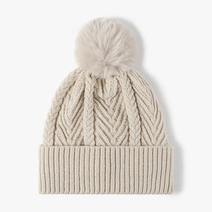 Beige chevron knit pom beanie with ribbed cuff and cable knit details.