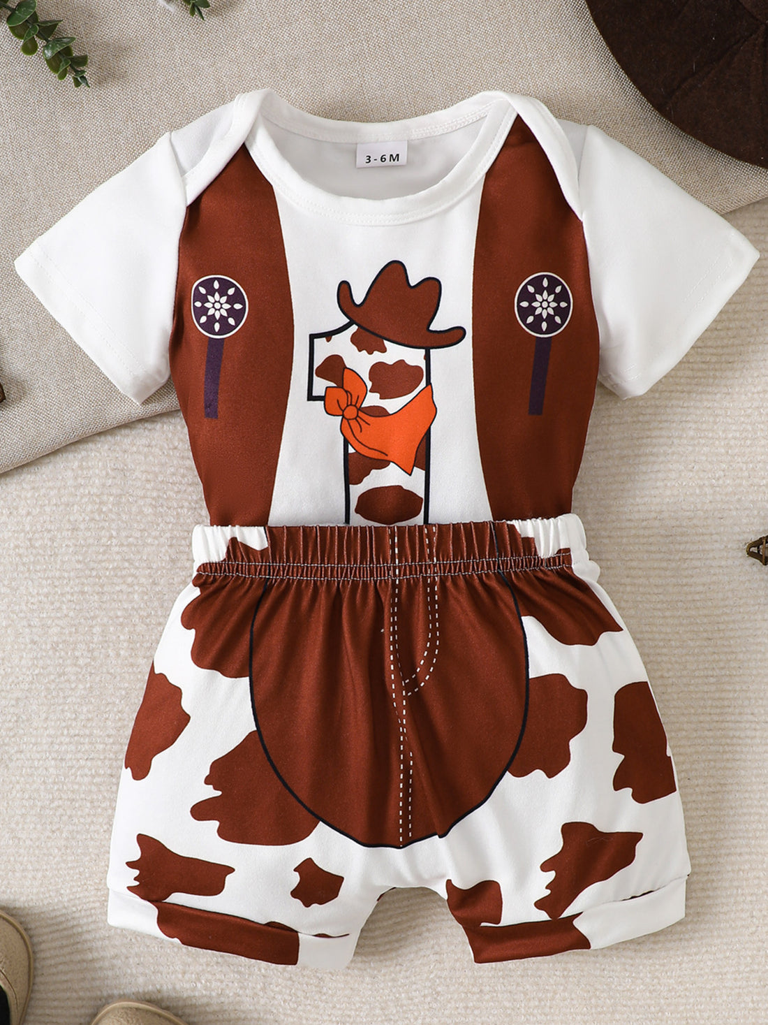 Baby bodysuit and shorts set with cowboy theme, cow print shorts and number 1 graphic.