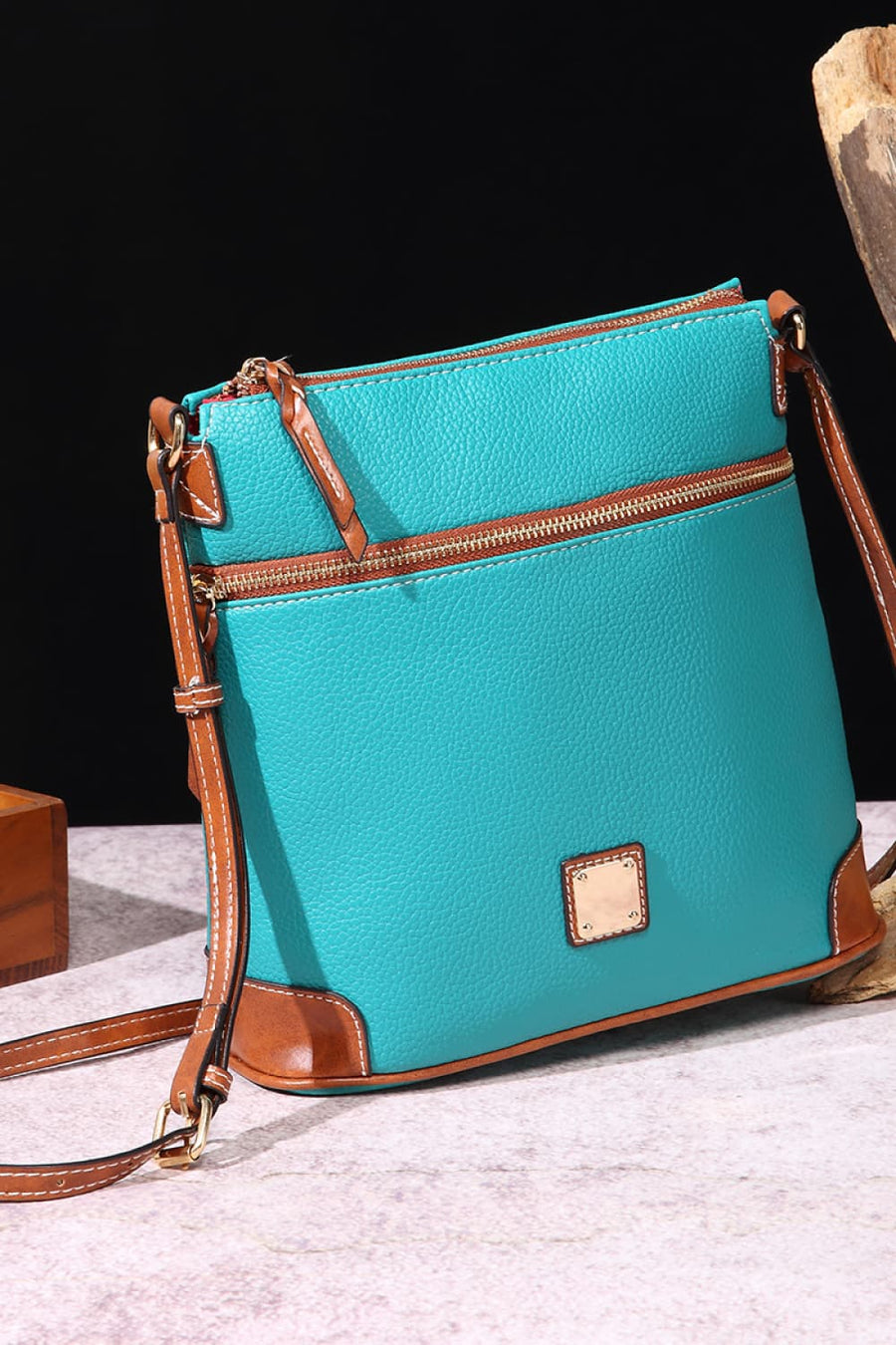 Turquoise leather crossbody bag with brown trim and gold hardware.