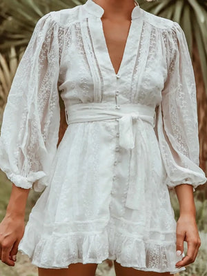 White lace mini dress with V-neck, bishop sleeves, and tie waist.