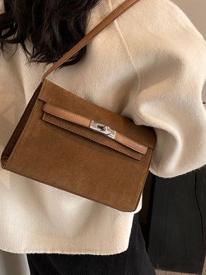 Brown suede shoulder bag with a silver buckle closure and tan leather trim.