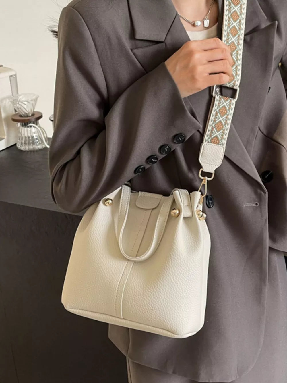 Textured crossbody bag in Rice White with a unique patterned strap and gold hardware.