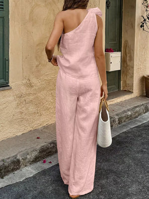 Pink linen one-shoulder top with bow detail and wide-leg pants set.