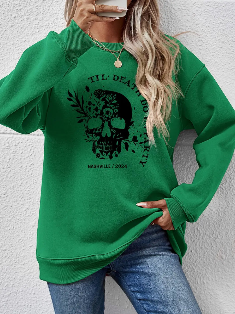 Green crewneck sweatshirt with floral skull graphic and text.