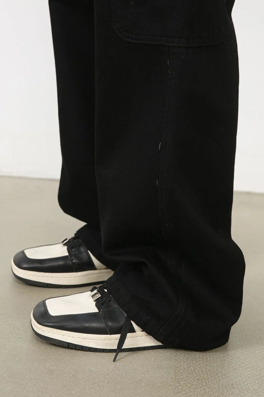 Black pleated cargo denim trousers with a relaxed fit, detailed view of pockets and stitching.