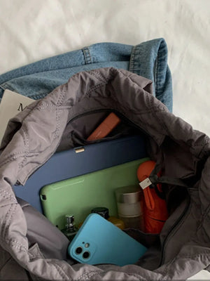 Diamond quilt nylon tote bag in gray, showing interior contents like phones and cosmetics.