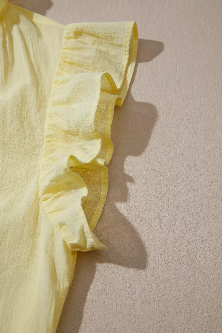 Yellow cotton blend shirt with ruffled cap sleeves and V-neck detail.