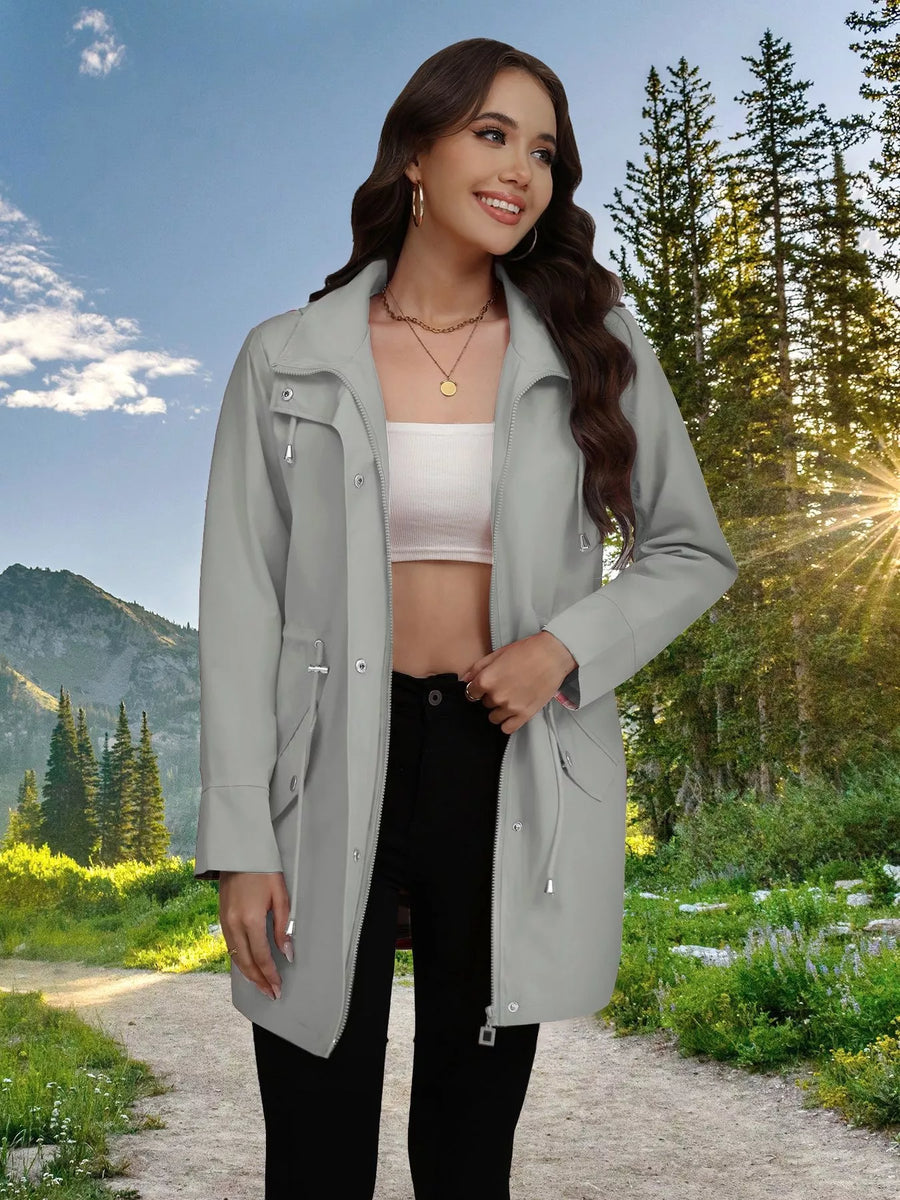 Light gray drawstring trench coat with snap-down front and zippered pockets.