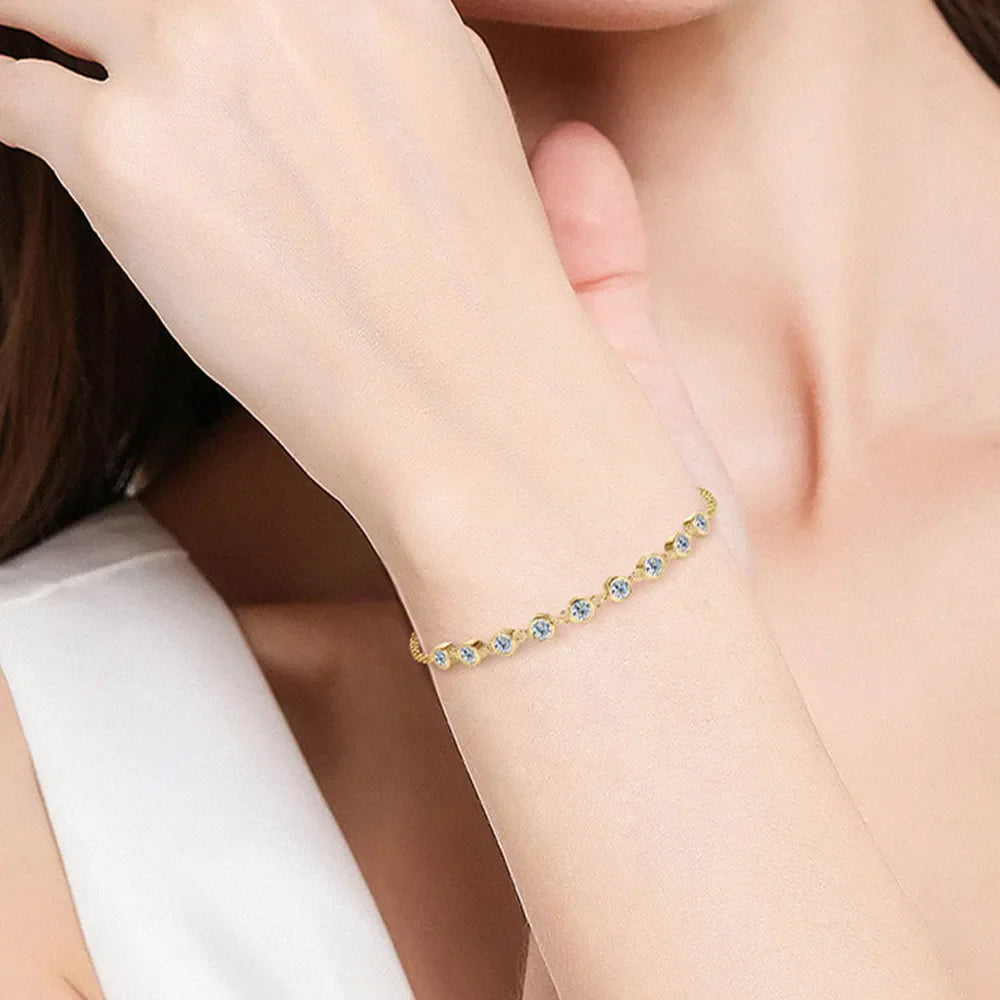 Gold bezel-set moissanite tennis bracelet with a delicate chain.