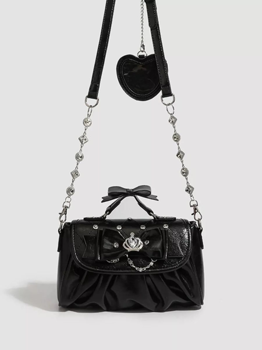 Black ruched crossbody bag with bow, crown detail, and heart charm.