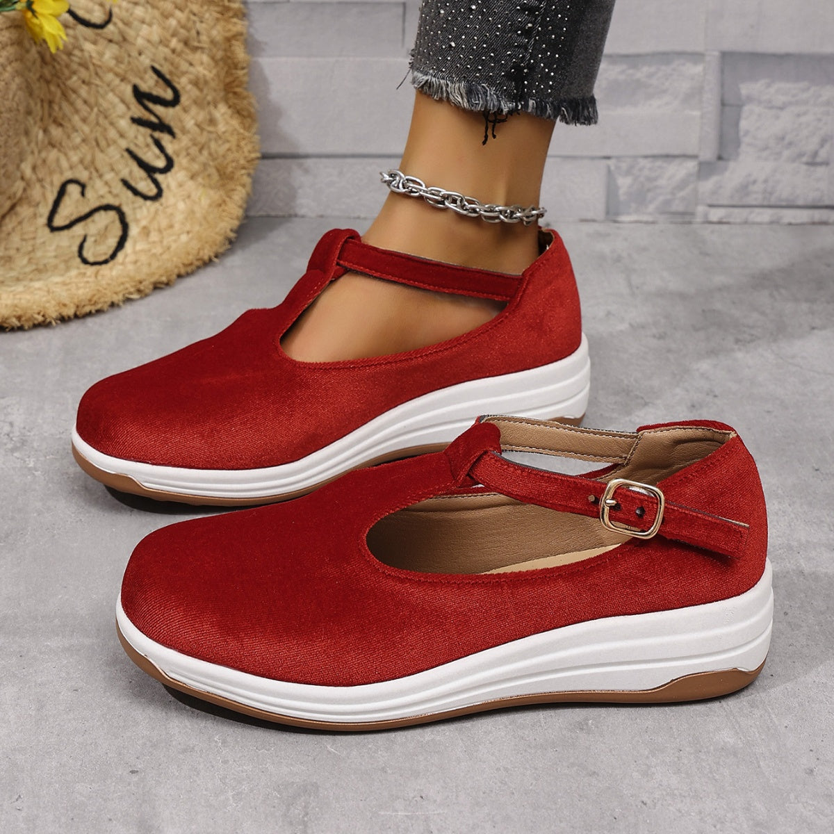 Red T-bar flat slip-ons with adjustable strap and buckle detail.