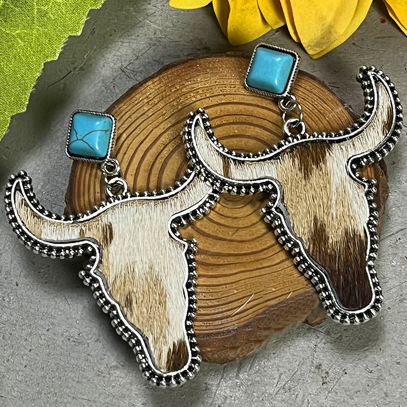 Cowhide bull head earrings with turquoise square tops and silver beaded trim.