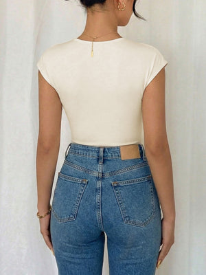 Cream cap sleeve bodysuit with surplice neckline, paired with high-waisted denim jeans.