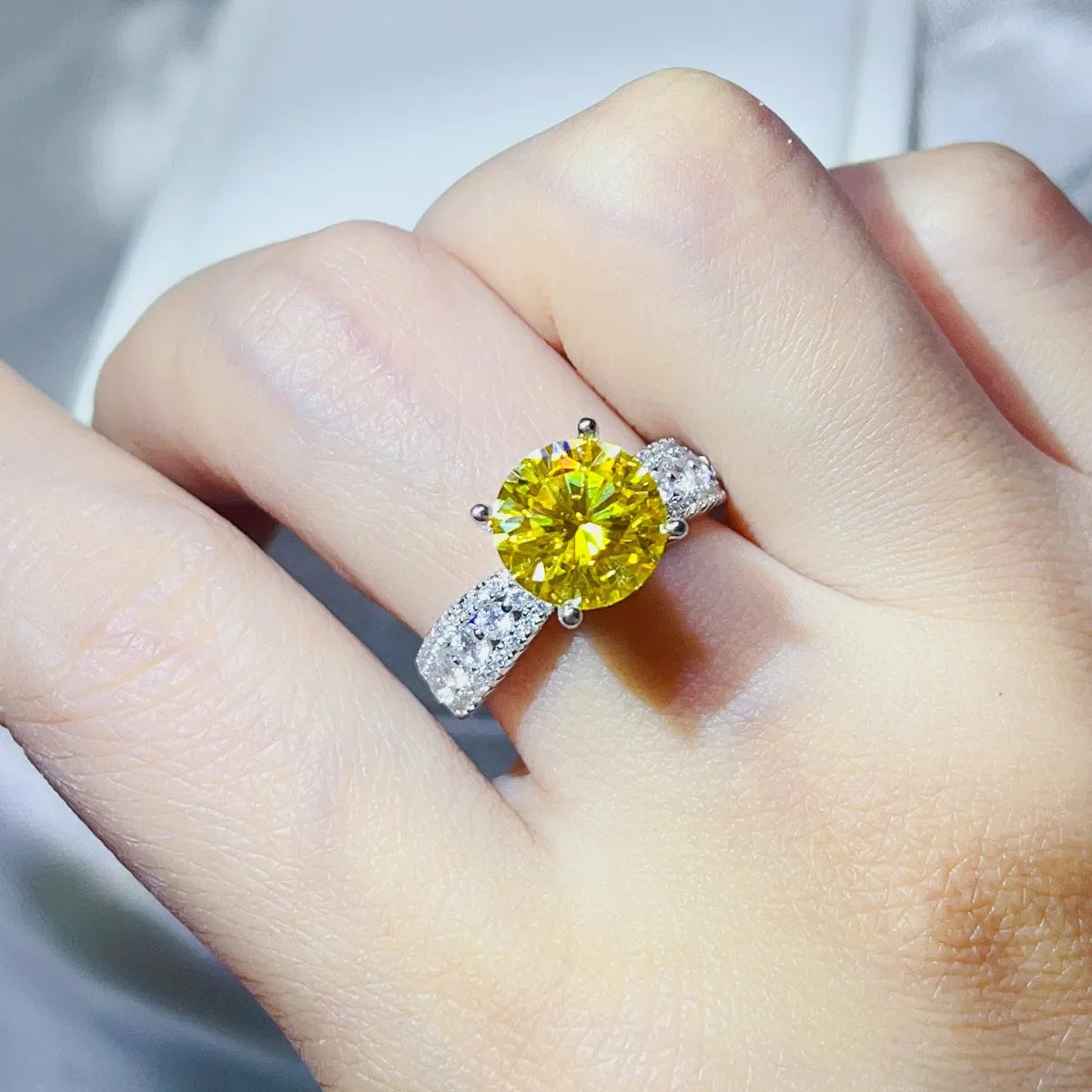 Yellow moissanite pavé band ring with a large center stone on a hand.