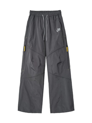 Graphite gray relaxed fit cargo pants with drawstring and yellow zipper accents.