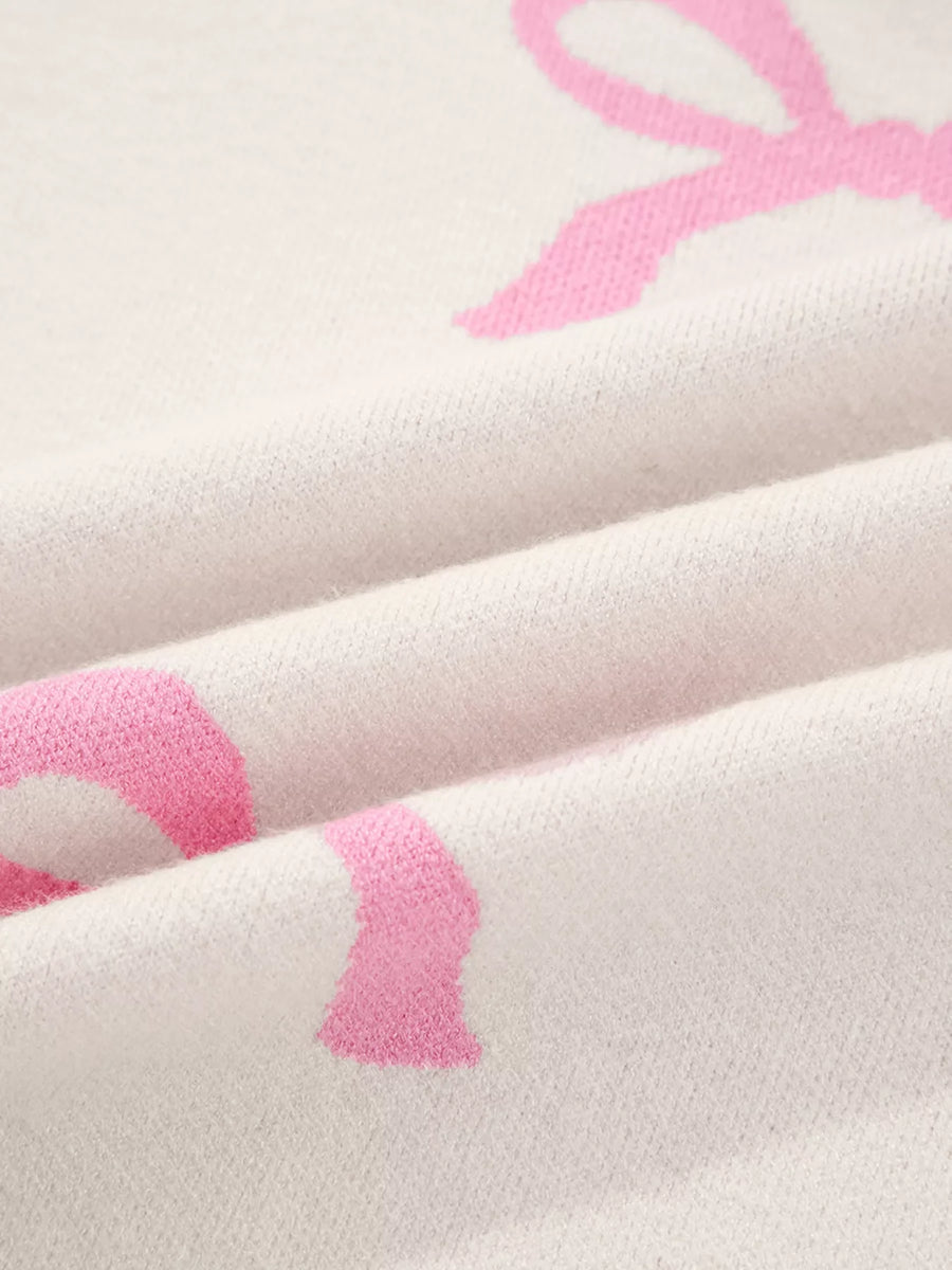 Beige acrylic blend sweater with a pink bow print and a soft knit texture.