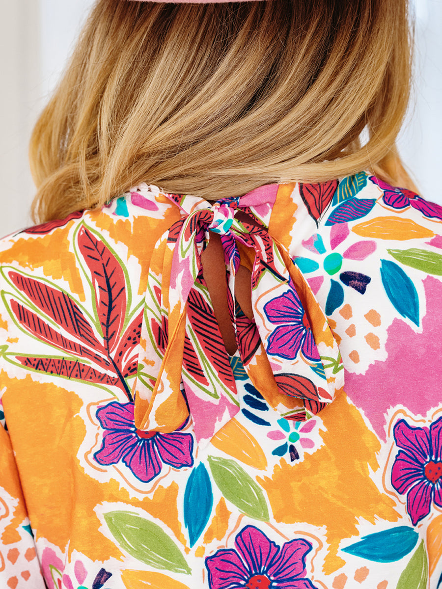 Print bell sleeve mini dress with colorful floral pattern and tie-back detail.