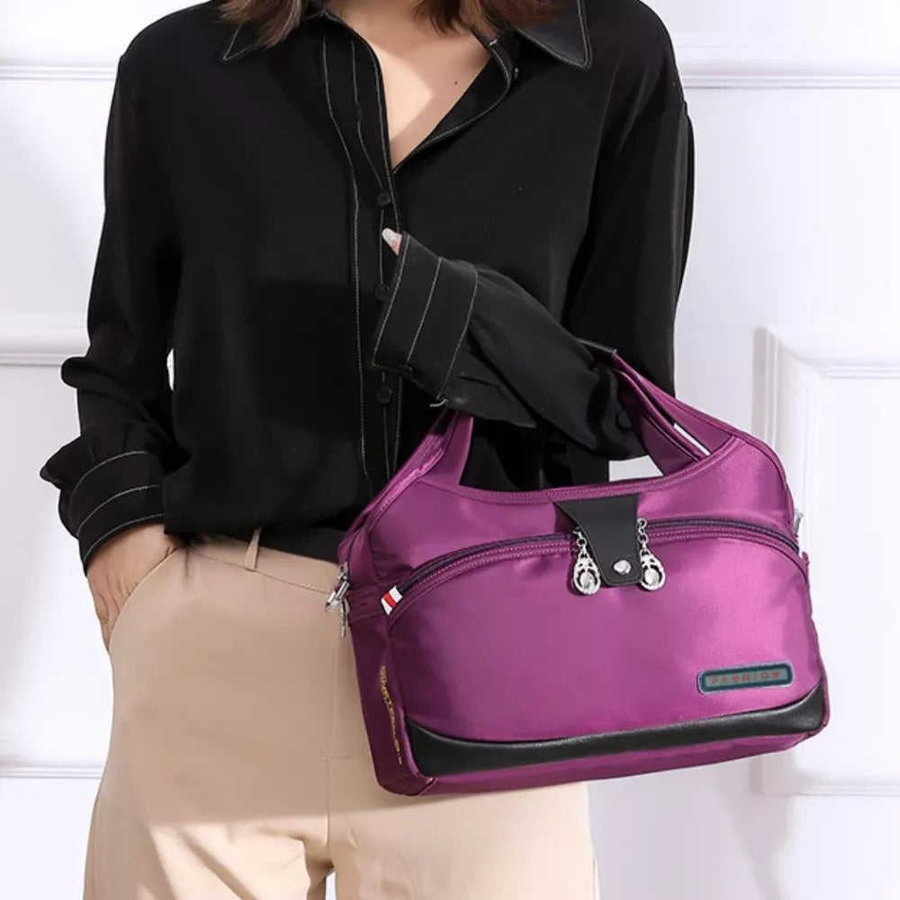 Spacious purple nylon tote bag with decorative charms and black trim.