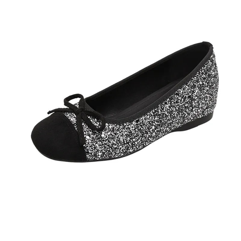 Glitter cap-toe ballet flats in silver with a black toe cap and bow detail.