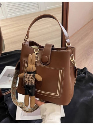 Brown pu leather bucket crossbody bag with decorative stitching and bunny charm