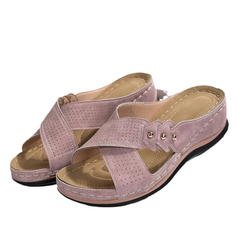 Pink perforated cross-strap comfort sandals with decorative studs.
