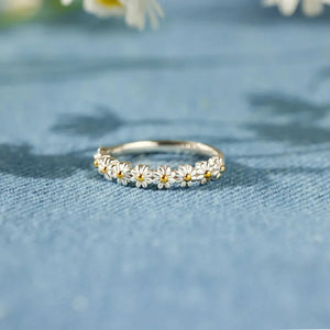 Silver band ring with a continuous daisy chain pattern and yellow centers.