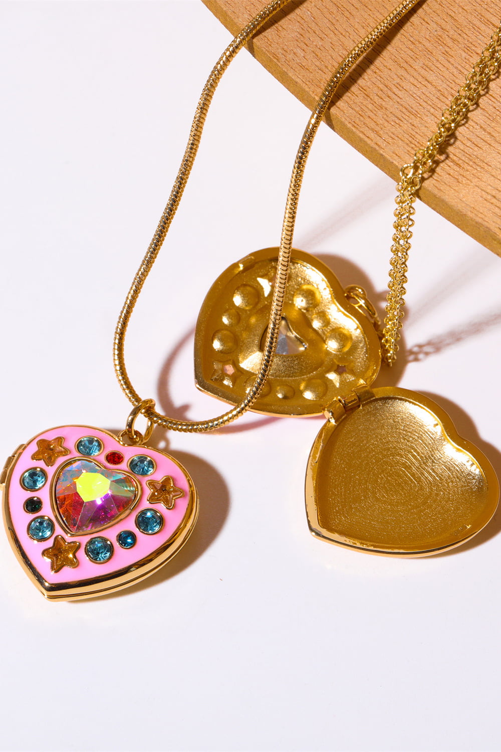 Gold heart locket necklace with pink enamel, iridescent gem, and blue stones
