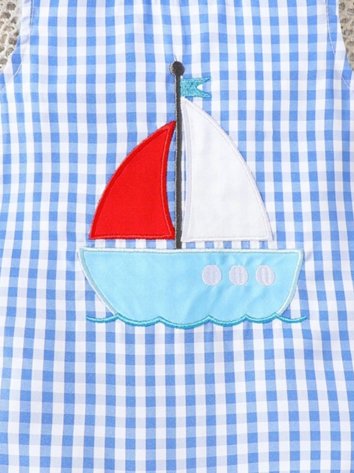 Blue gingham one-piece with sailboat appliqué and red sail.