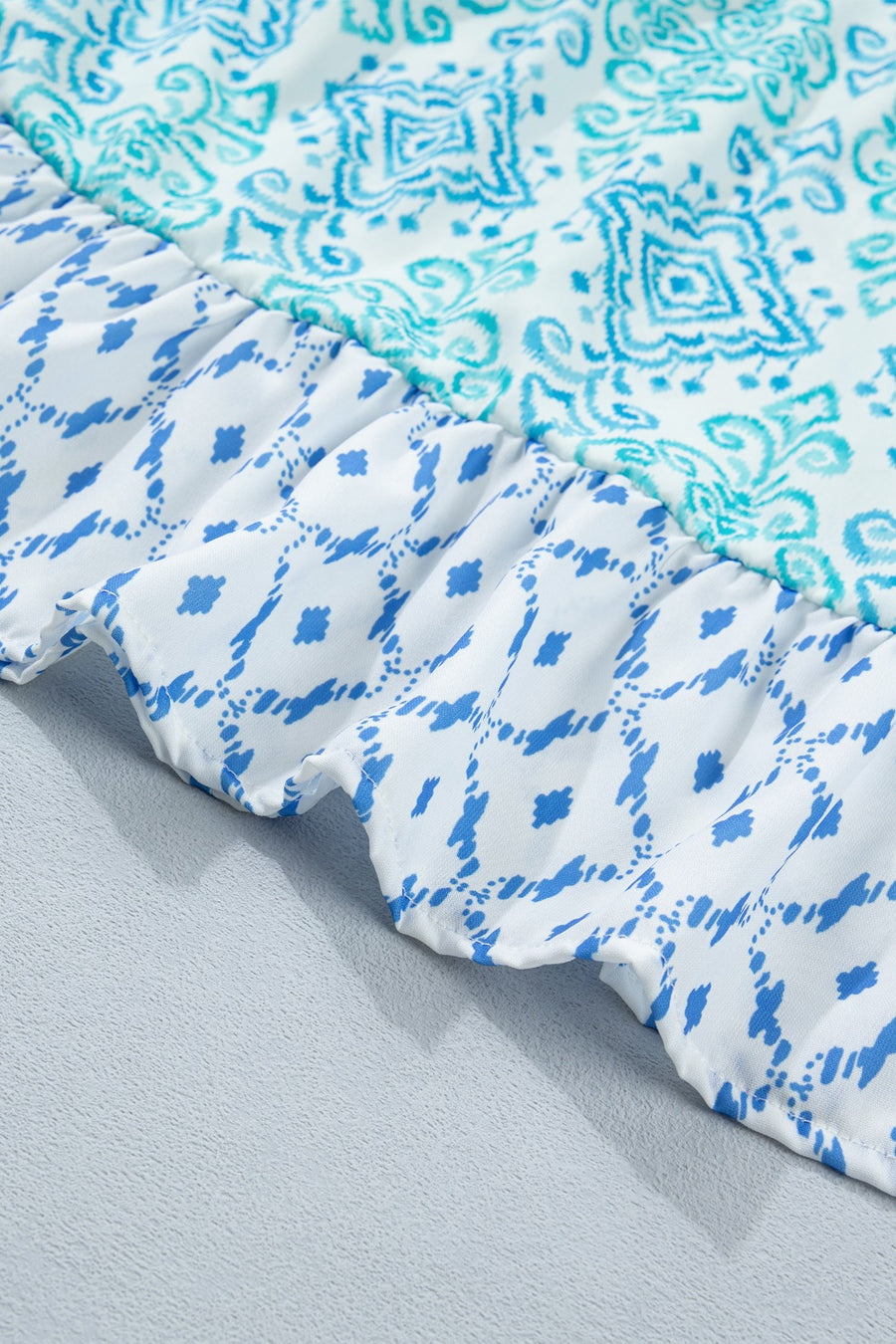 Patchwork mini dress with blue and white abstract prints and ruffled hem.